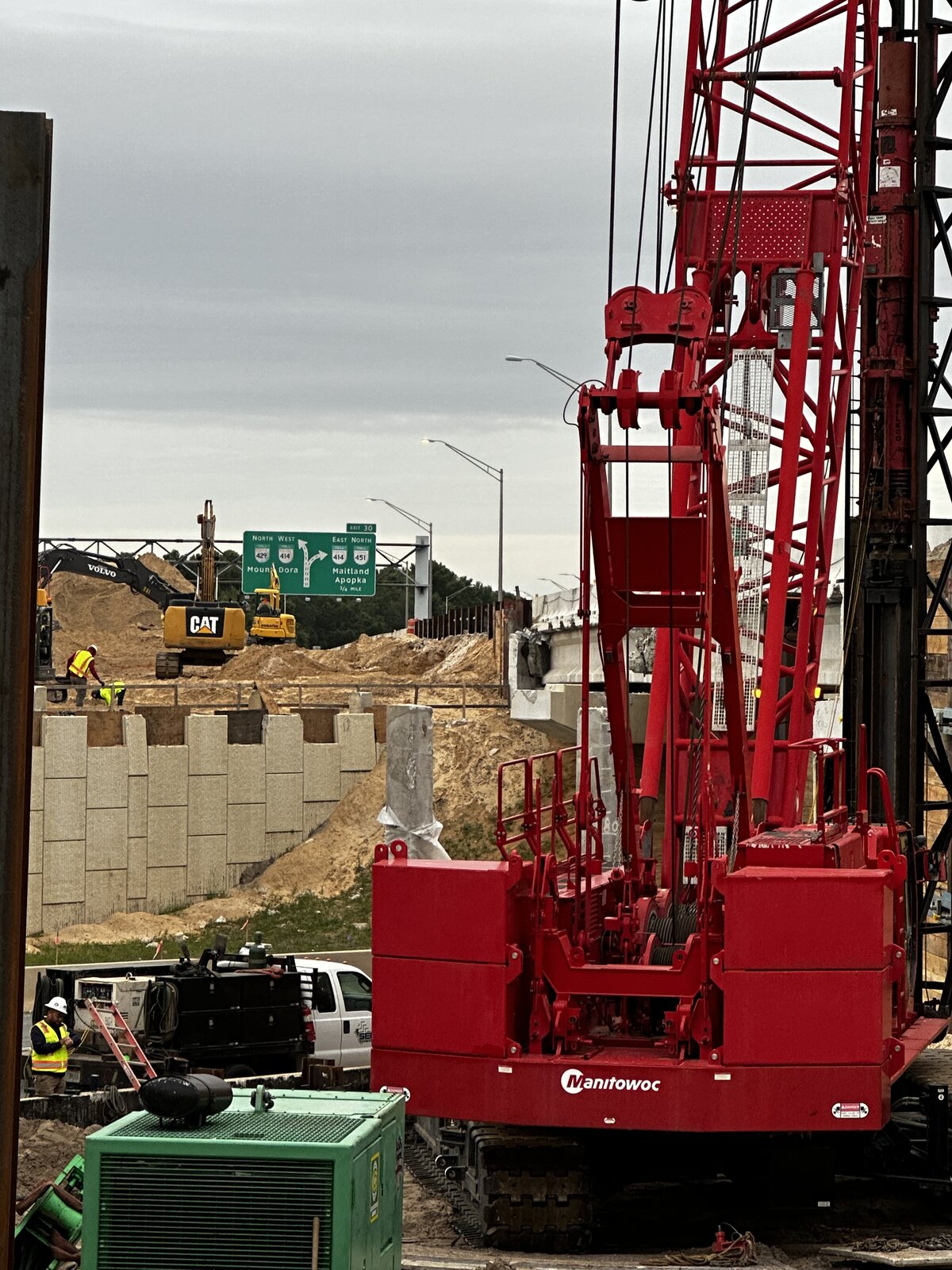 Red crane driving sheet pile wall at construction site